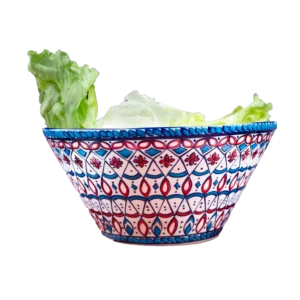 Cuenco de cerámica artesanal decorado con patrones geométricos en azul y rojo, con hojas de lechuga en su interior.