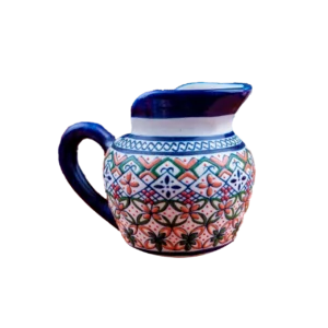 Jarra de cerámica artesanal con asa y pico vertedor, decorada con patrones geométricos y florales en tonos azul, verde y naranja sobre fondo claro.