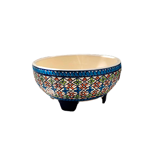 Cuenco de cerámica artesanal con base elevada, decorado con patrones geométricos multicolores y borde azul sobre fondo claro.